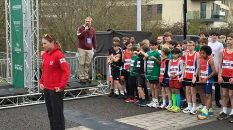 BBC Carys Westcott in black trousers and a red hoodie starting the Green Park Challenge ahead of the Reading half marathon