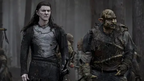 Amazon Prime Video Characters from the show The Ring of Power, which has been filmed at Bray Studio. An elf and an orc can be seen in the image in what is a dark wooded scene