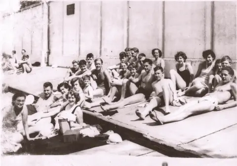 Ken Norman/Broomhill Pool Trust A black and white photo of people sitting or lying on the hard surface at Broomhill Pool