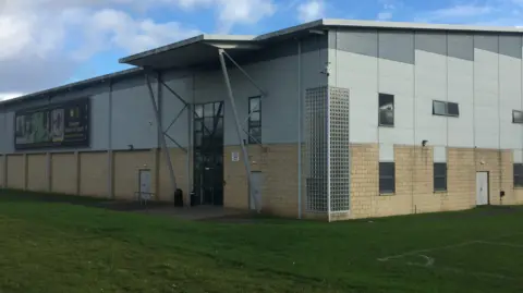 The Glasgow School of Sport building - playing fields are outside the building, which is a mix of sandstone bricks and grey/white. 