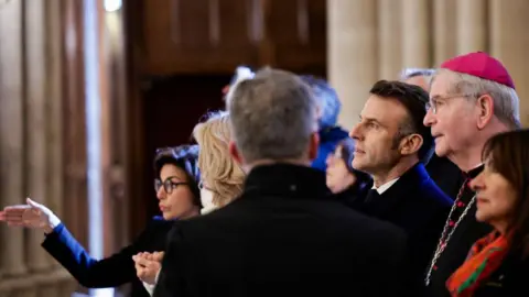 Getty Images From (C-L) French President Emmanuel Macron, Paris' archbishop Laurent Ulrich and Paris' mayor Anne Hidalgo look up during a visit of Notre-Dame de Paris cathedral in Paris, on November 29, 2024. 