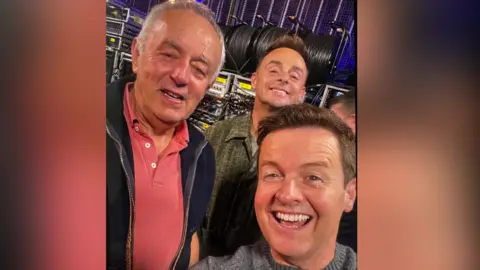 Hugh is pictured wearing a pink polo with a smiling Ant and Dec.