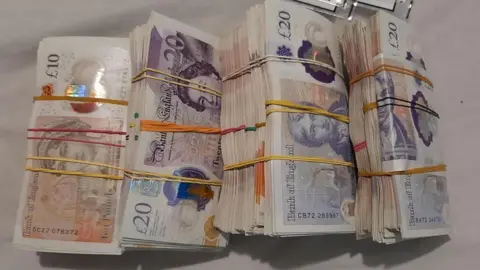 Four bundles of British ten and twenty pound notes tied together with rubber bands