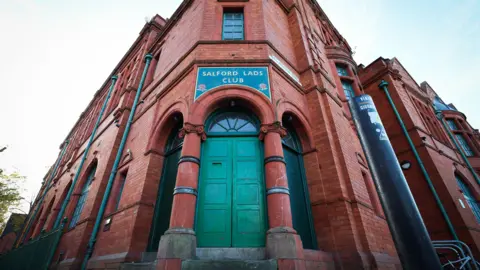 EPA The green door at the entrance to the red brick Salford Lads Club, with two red columns either side. 