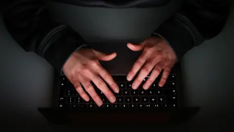 A close up of two hands typing on a laptop keyboard.