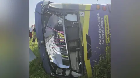 Jacko Thomas A purple bus is seen lying on its side in a field