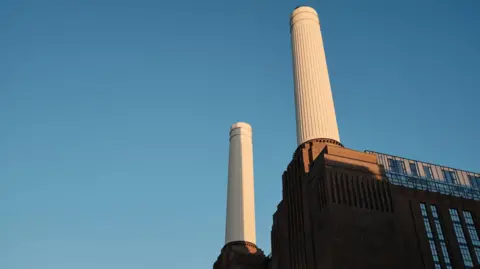 Battersea Power Station stands against a backdrop of a clear blue sky.