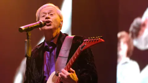 Getty Images Wayne Osmond memainkan gitar