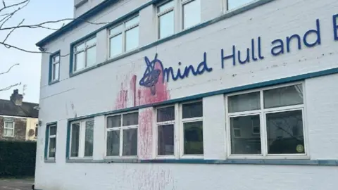 The outside of the Hull and East Yorkshire Mind building with red paint splattered over the front of the white building and also over the dark blue signage