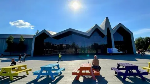 People sitting at picnic tables outside Glasgow transport museum