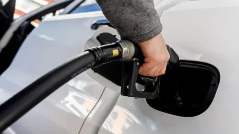 A close up image of someone pouring petrol into their car at a pump in New York last week