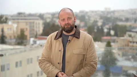 James Waterhouse in a brown jacket with Jerusalem in the background