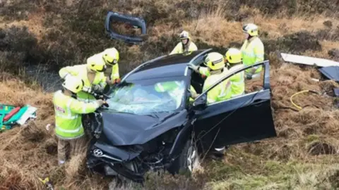 A car in a ditch by the side of the road.