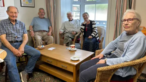 Five people at Dursley Day Centre, sat around a coffee table in wicker chairs