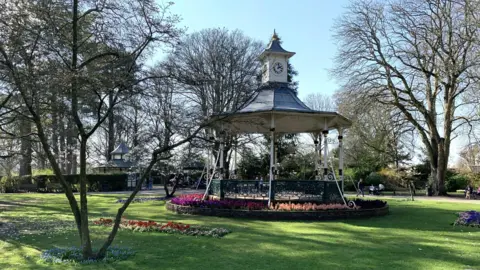 Swindon's Town Gardens with the bandstand thrown into shade with freshly planted plants.