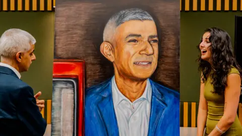 Paris Higson Tia Mirza and Sadiq Khan appear to share a joke as they stand either side of the portrait.