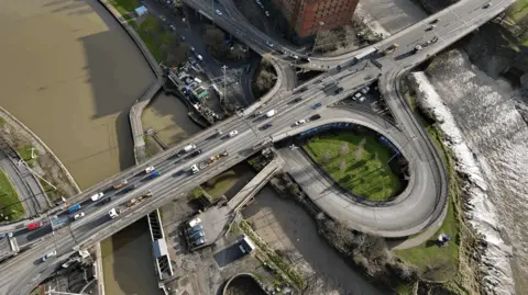 Plimsoll Bridge seen from above. It is a busy dual carriageway over water. There are other roads looping off and under it.