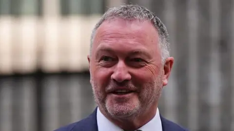 Environment Secretary Steve Reed. He is smiling and wearing a navy blue suit jacket with a white collared shirt
