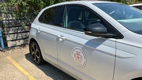 A car with a large, printed crest on the side which reads "Chief Judge Mark-kishon Christopher".
