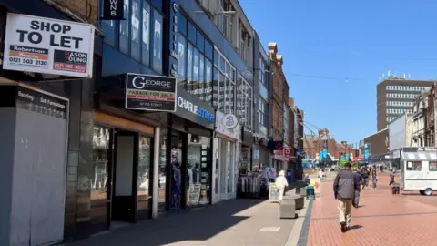 High Street avec des magasins vides et des gens marchant le long de la route