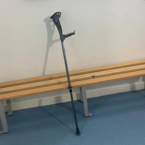 Wasdale Mountain Rescue Team A grey crutch leaning against a wooden bench and white wall.