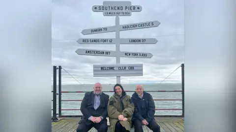 Southend-on-Sea City Council Two men and one women sitting in front of new selfie signpost at Southend-on-Sea pier