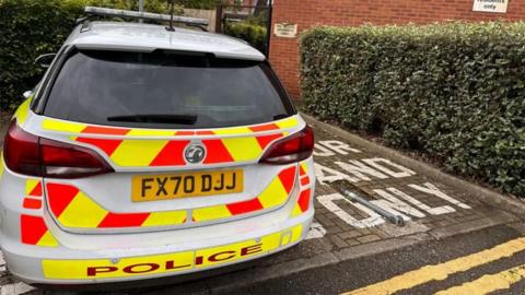 Police car parked outside the flats in Lincoln where Marc Glasscoe's body was found