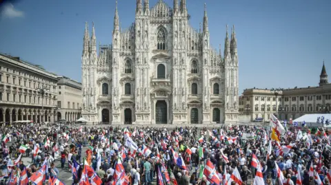 EPA People gather with flags in a square outside a large cathedral 