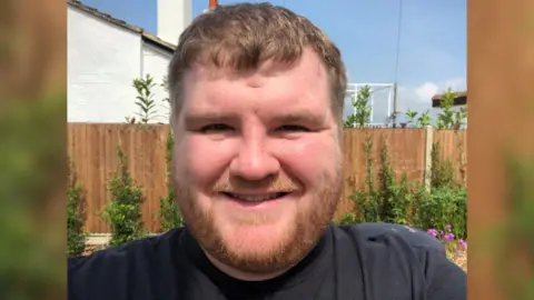 Ethan Lawrence taking a selfie in a garden smiling at the camera