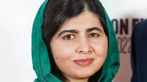 Press Association Malala Yousafzai smiles at the camera. She is wearing a dark green hijab.