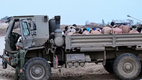 Reuters Israeli soldiers stand by a military truck carrying Palestinian detainees in the Gaza Strip (December 8, 2023)