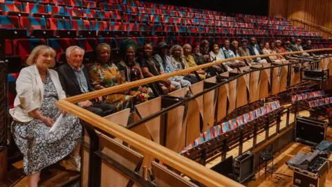 Bristol Beacon A row of people sit in sits at the Bristol Beacon to honour members of the Windrush generation