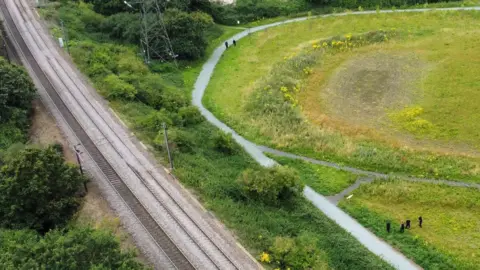 John Fairhall/BBC A drone shot showing how close the railway line is to the area being searched by police officers