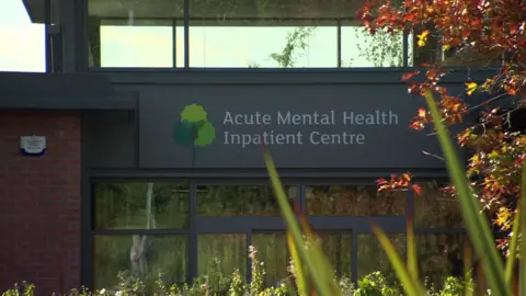 BBC Red brick building with grey sign reading 'Acute Mental Health Inpatient Centre'