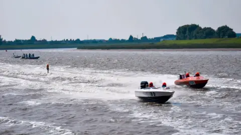 Borough Council of King's Lynn and West Norfolk View of two small boats - one white, one red, racing along the River Great Ouse.