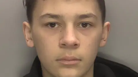 West Midlands Police Custody photograph of Kian Moulton released by West Midlands Police. The image shows a teenage boy in a black hoodie photographed against a plain background. 