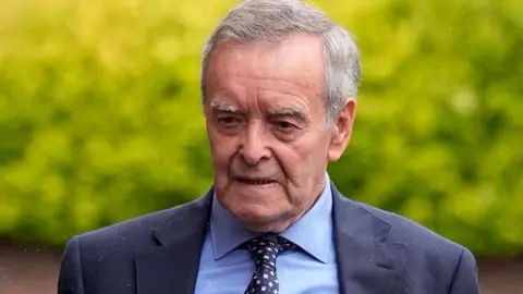 PA Media Willy Leeson, father of Paula Leeson arriving at Manchester South Coroner's Court, Stockport, for the inquest into her death. He has short grey hair and is wearing a blue shirt, navy patterned tie and navy suit jacket