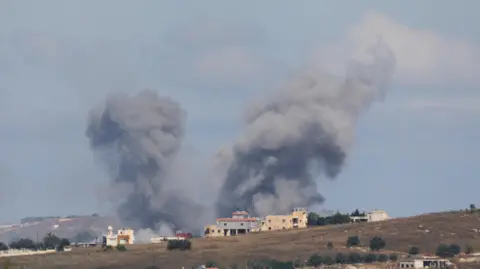 Plumes of smoke are seen above a house