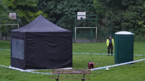 PA Media A black forensics tent seen in the middle of a park inside an area cordoned off by police tape