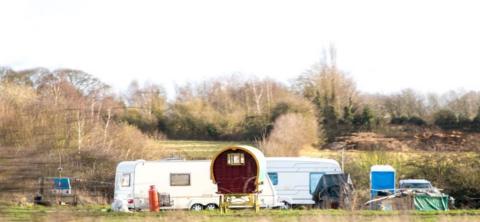 A typical Gypsy camp site set up in a field at the side of a motorway