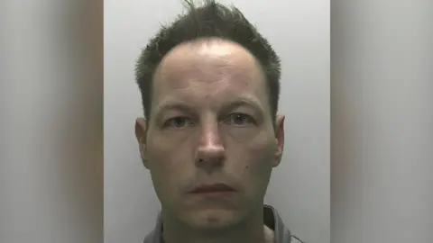 Devon and Cornwall Police A mugshot of Redmond with short dark hair and a white-ish background.