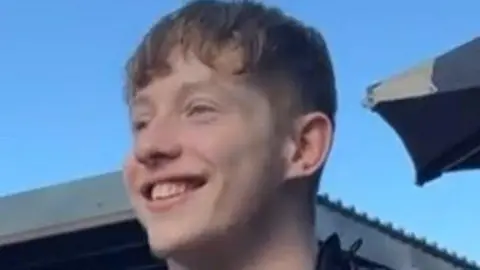 A young man smiling with blue skies in the background