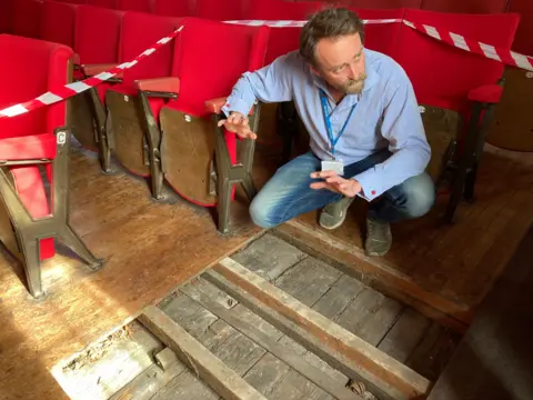 Guildhall creative director Tim FitzHigham crouching above floorboards dating back to the time that William Shakespeare was thought to have performed in King's Lynn. 