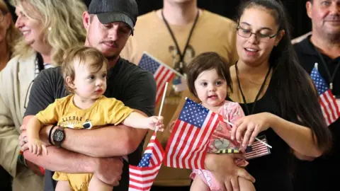 White South African parents holding their two children with small American flags 