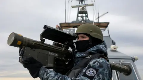 A Ukrainian soldier holds a large anti-aircraft gun on board a boat in the Black Sea