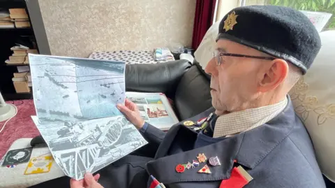 Kevin Shoesmith/BBC Cliff Dalton looks at photos showing the floating Mulberry harbours