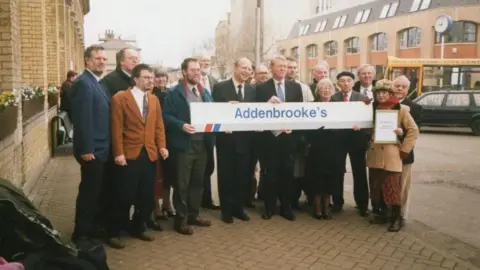 Cambridge Liberal Democrats A photo from the 1990s of the once Cambridge Liberal Democrats who are standing on a pavement holding a sign that says Addenbrooke's.