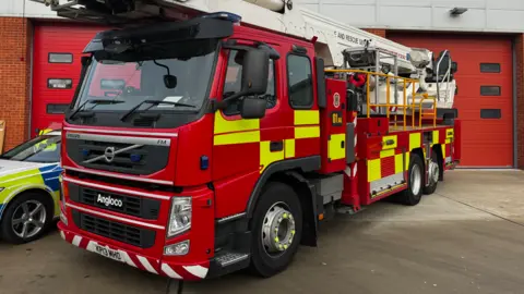 A Suffolk Fire and Rescue Service fire engine parked in front of a fire station.