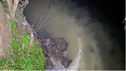 Environment Agency A sewage discharge into a river.