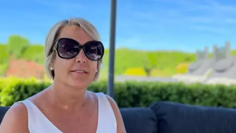 A woman in shades sat in her garden